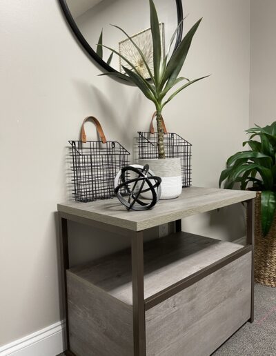 A modern console table with decorative items including a plant, geometric sculpture, and storage baskets.