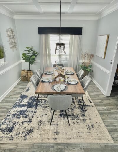Modern dining room with a wooden table, black chairs, and decorative accents under a pendant light.