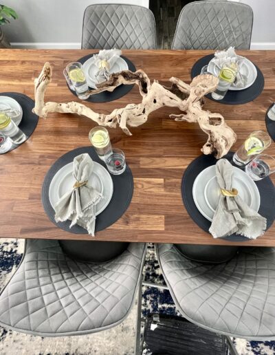 Elegantly set modern dining table with decorative centerpiece and place settings for four.