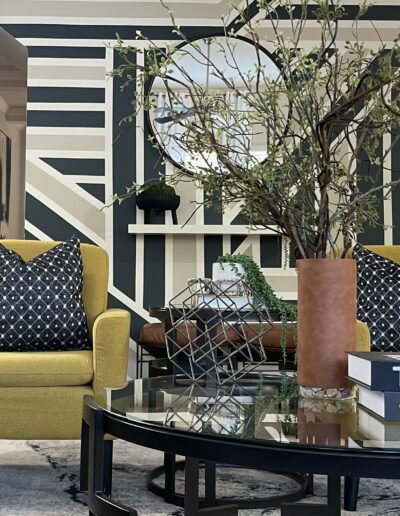 A stylish interior with two yellow armchairs, patterned cushions, and a selection of designer coffee table books.
