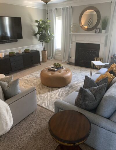 A cozy, well-lit living room featuring a sectional sofa, an ottoman coffee table, a fireplace, and decorative elements creating a warm ambiance.