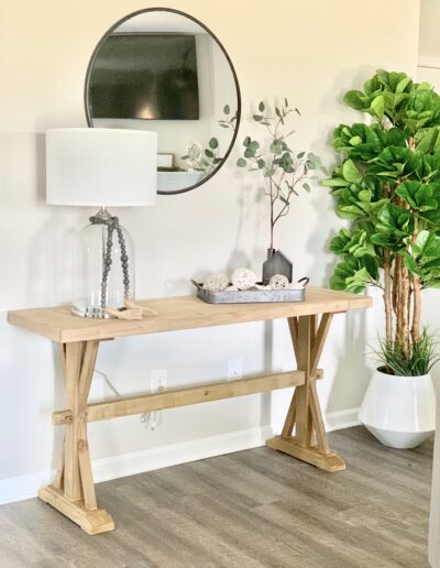 A well-lit, modern entryway with a wooden console table, decorative objects, a round mirror, and indoor plants.