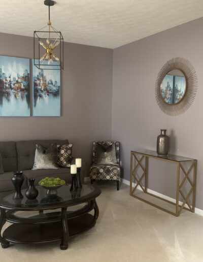 A modern living room with a gray sofa, matching chairs, a round coffee table, and abstract art on the wall.