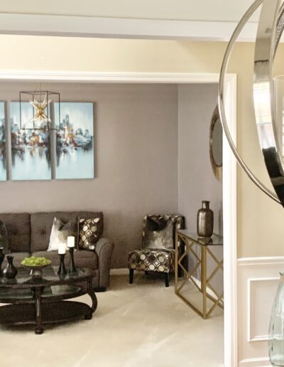 Modern living room with neutral tones, featuring a sofa set, a round coffee table, decorative pieces, and artwork on the wall.